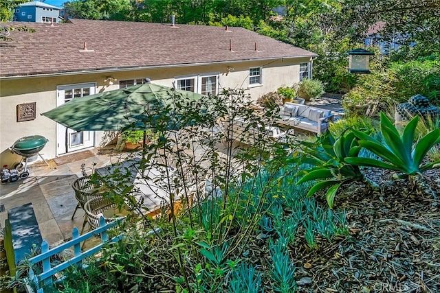 exterior space featuring a patio area, a shingled roof, and stucco siding