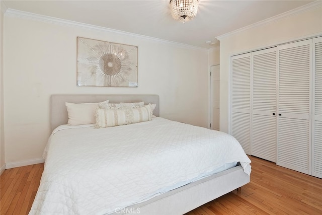 bedroom with a closet, baseboards, crown molding, and wood finished floors