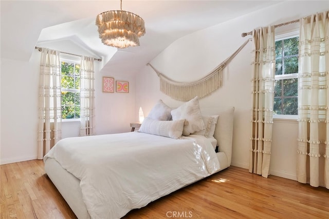 bedroom featuring baseboards, vaulted ceiling, and light wood-style floors