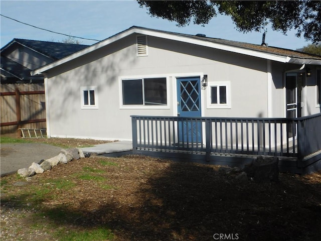 back of property featuring fence, a deck, and stucco siding