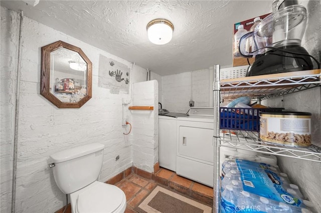 bathroom featuring toilet, washing machine and dryer, and a textured ceiling