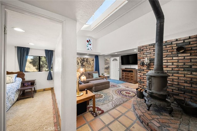 living area featuring recessed lighting, baseboards, lofted ceiling with skylight, a wood stove, and light tile patterned flooring