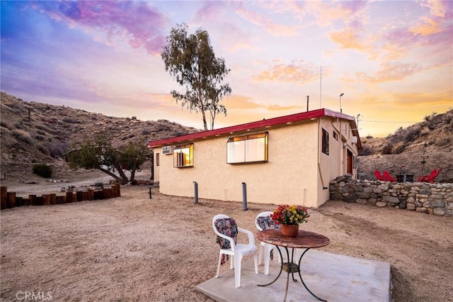 property exterior at dusk with a patio and stucco siding