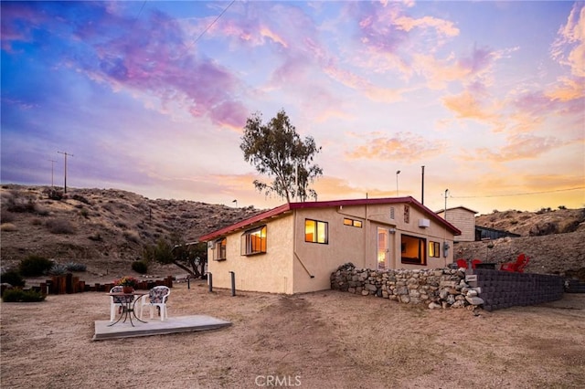 rear view of house with stucco siding and a patio