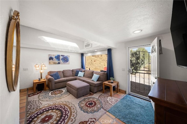 living room with visible vents, a textured ceiling, and light tile patterned flooring