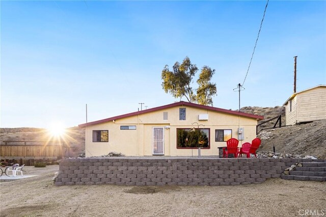 rear view of house featuring a patio area, fence, and stucco siding