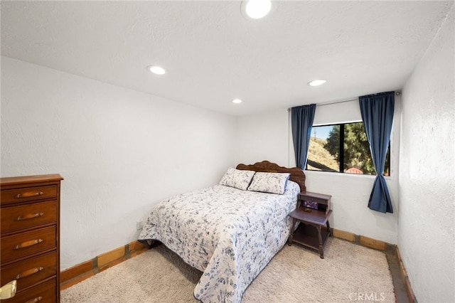 carpeted bedroom featuring a textured wall, baseboards, and recessed lighting