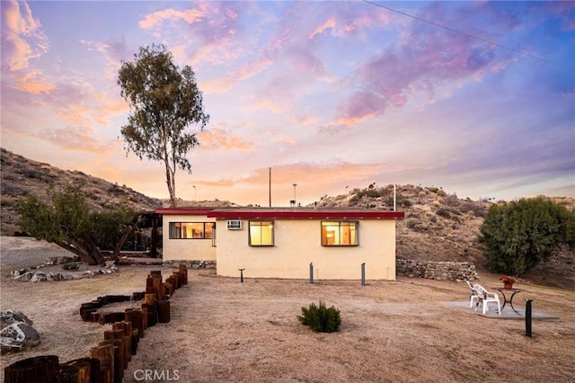 back of house at dusk featuring stucco siding