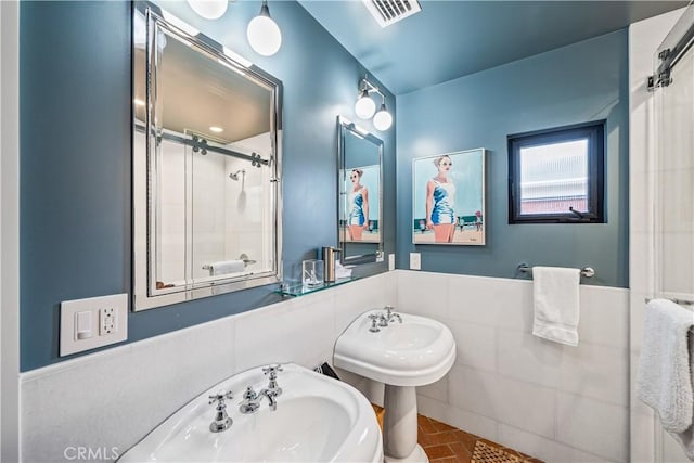 bathroom featuring brick floor, an enclosed shower, and visible vents