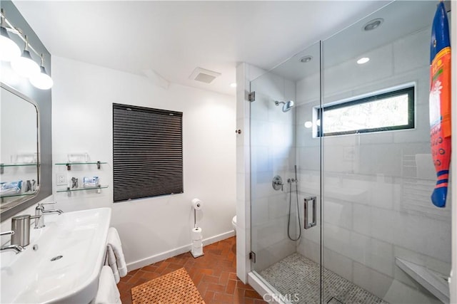 full bathroom with brick floor, toilet, a sink, a shower stall, and baseboards