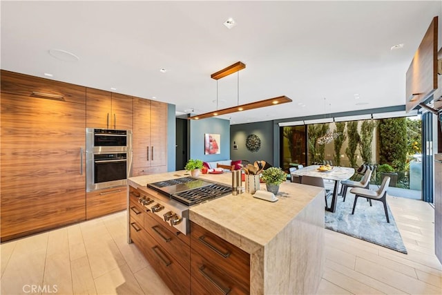 kitchen featuring modern cabinets, appliances with stainless steel finishes, a center island, light countertops, and pendant lighting