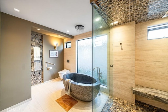 full bath with a freestanding bath, tiled shower, toilet, and baseboards