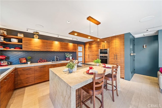 kitchen with a breakfast bar, a center island, brown cabinets, light countertops, and appliances with stainless steel finishes