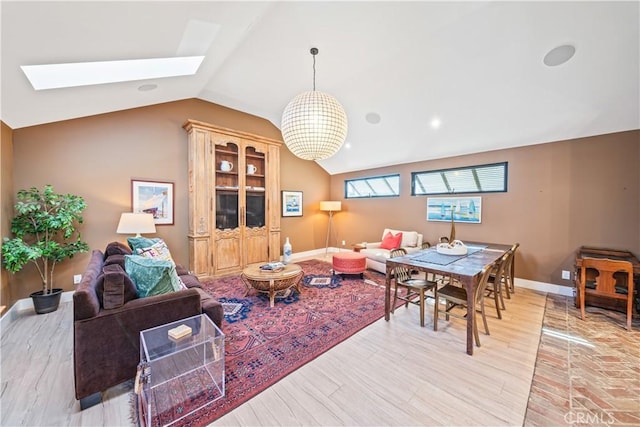 interior space with lofted ceiling with skylight, light wood-style flooring, and baseboards