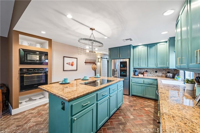 kitchen with visible vents, a kitchen island, hanging light fixtures, brick floor, and black appliances