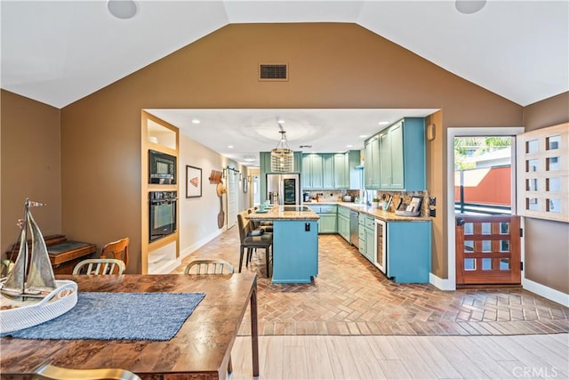 kitchen featuring visible vents, a breakfast bar area, a center island, light countertops, and black appliances