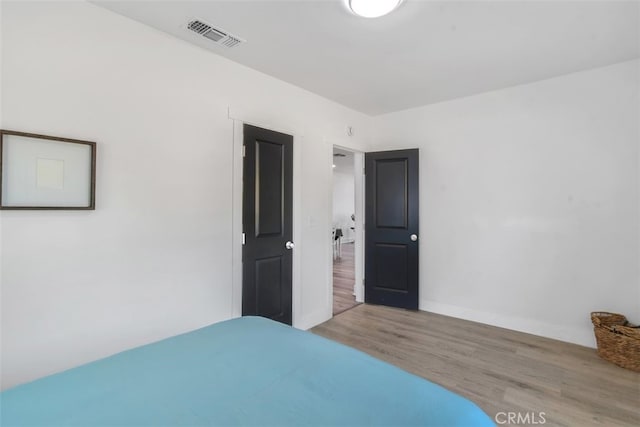 unfurnished bedroom featuring wood finished floors, visible vents, and baseboards