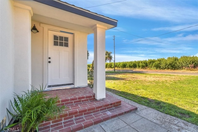 entrance to property with a lawn and stucco siding