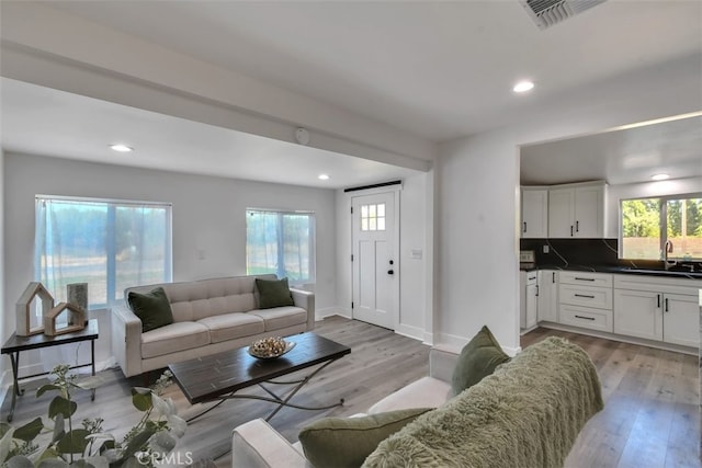 living room featuring a healthy amount of sunlight, visible vents, and light wood-style flooring