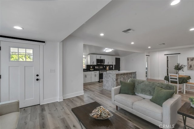 living area with recessed lighting, baseboards, visible vents, and light wood finished floors