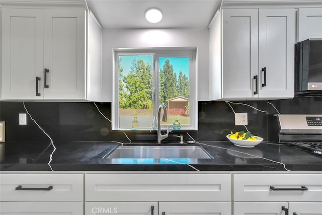 kitchen with black microwave, white cabinetry, and a sink