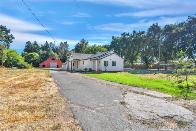 view of front of house featuring a detached garage, fence, a front lawn, and an outbuilding