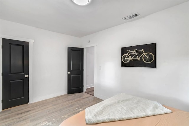 bedroom featuring wood finished floors, visible vents, and baseboards