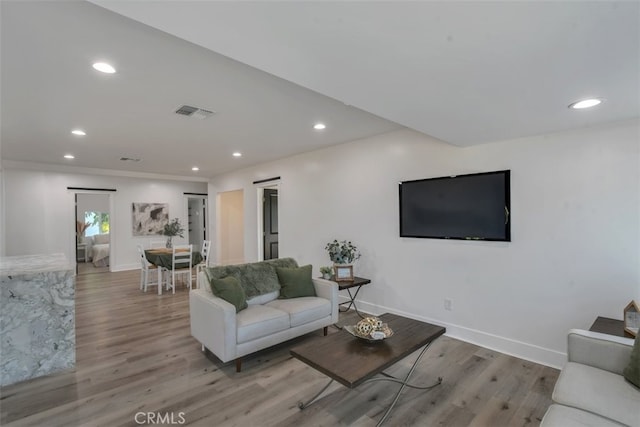 living area with baseboards, wood finished floors, visible vents, and recessed lighting