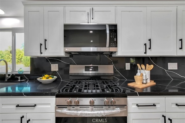 kitchen featuring dark countertops, tasteful backsplash, white cabinetry, and stainless steel appliances