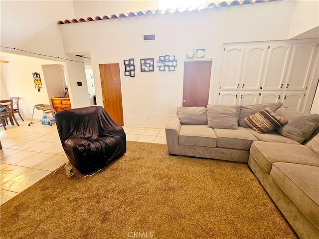 living room featuring a towering ceiling, light tile patterned floors, and visible vents