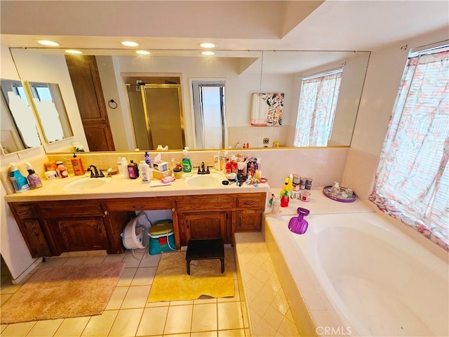 bathroom featuring double vanity, a garden tub, a sink, and a stall shower