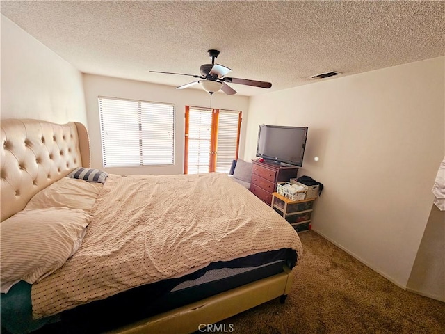 bedroom with carpet floors, a textured ceiling, visible vents, and a ceiling fan