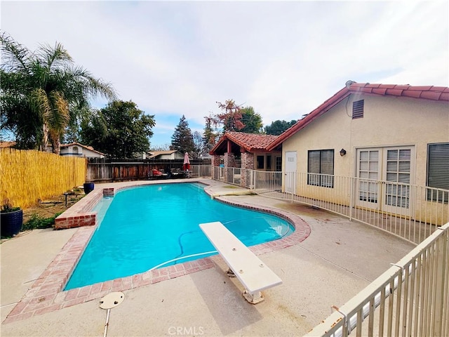 view of pool with a fenced in pool, a fenced backyard, a patio, and a diving board