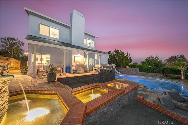 back of house featuring a fenced in pool, stucco siding, a patio, and an in ground hot tub