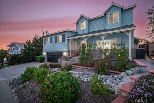 view of front of house with stone siding, decorative driveway, and an attached garage