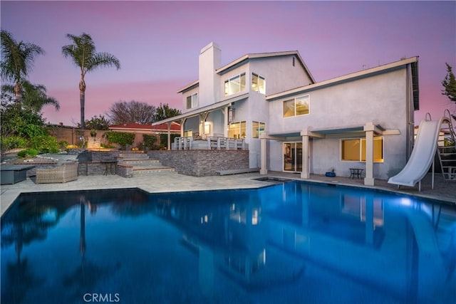 pool with outdoor dry bar, a water slide, a patio area, and fence