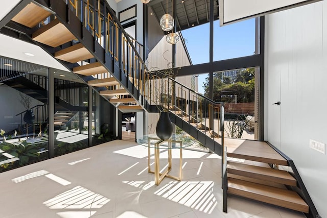 staircase with a wall of windows, a towering ceiling, and tile patterned floors