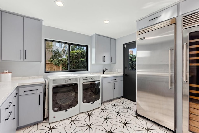 laundry area with recessed lighting, cabinet space, independent washer and dryer, and a sink