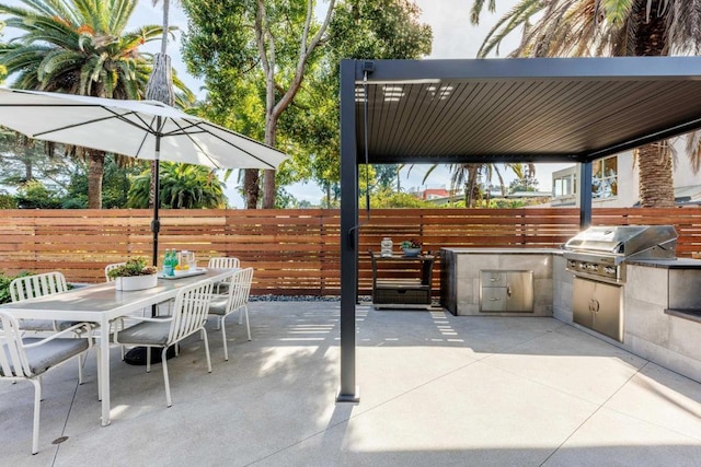 view of patio with outdoor dining area, fence, and area for grilling