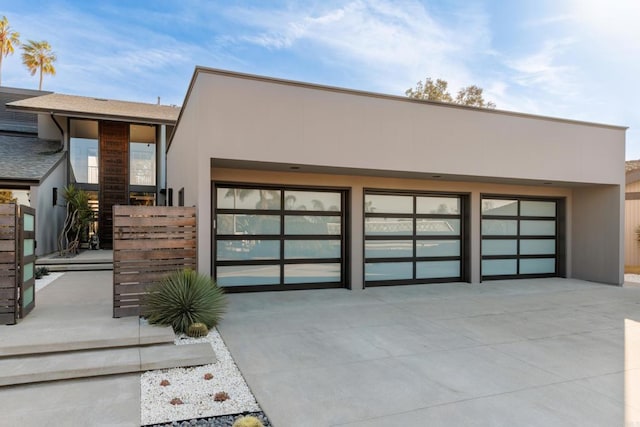 contemporary house with a garage, concrete driveway, and stucco siding