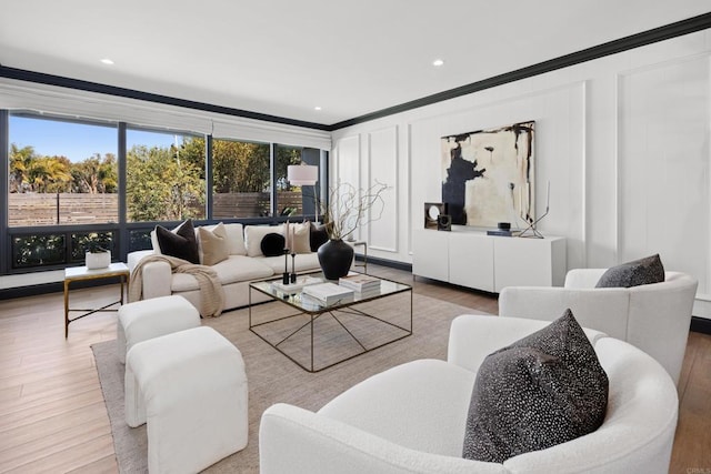 living area with ornamental molding, light wood finished floors, recessed lighting, and a decorative wall