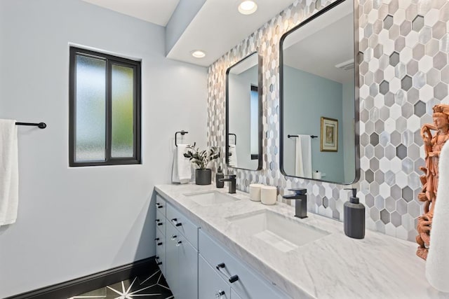 bathroom featuring baseboards, a sink, decorative backsplash, and double vanity