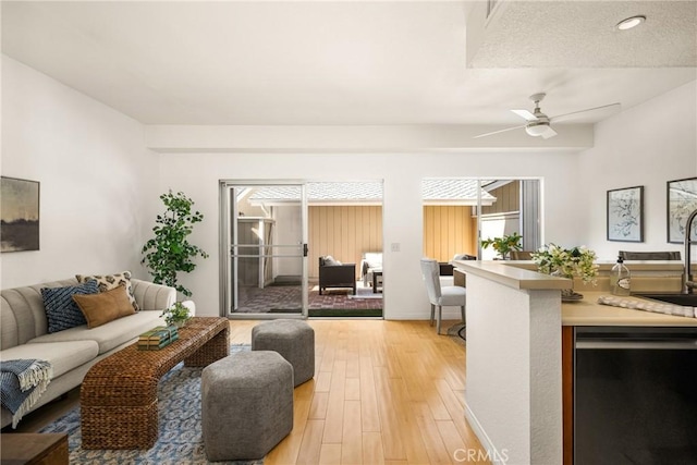 living area featuring ceiling fan, light wood-style flooring, and a healthy amount of sunlight