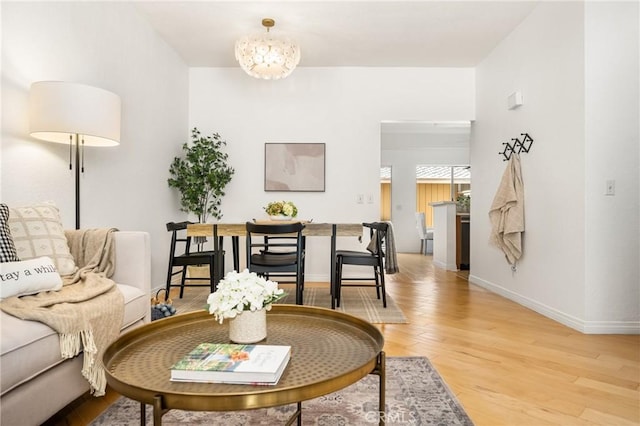 living area featuring a notable chandelier, light wood-type flooring, and baseboards