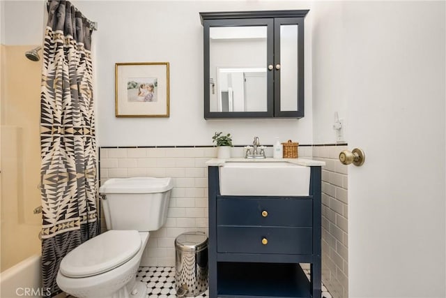 bathroom with toilet, vanity, tile walls, and wainscoting