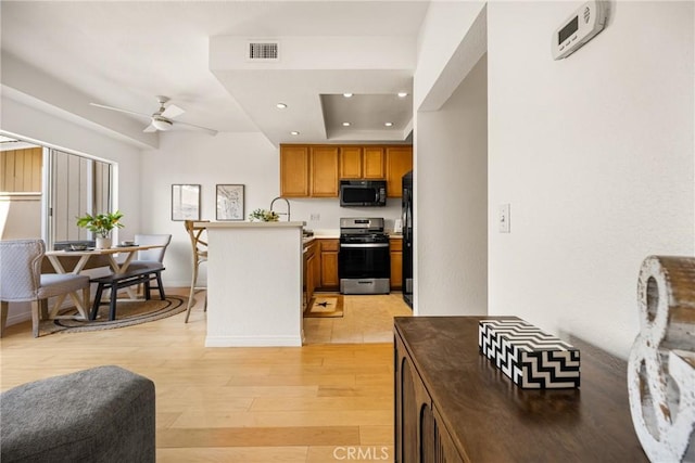 kitchen featuring brown cabinets, light wood finished floors, light countertops, visible vents, and black appliances