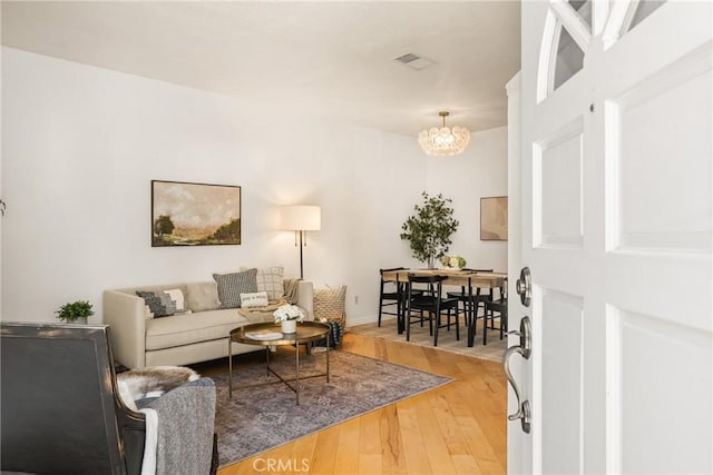 living area featuring visible vents, an inviting chandelier, and wood finished floors