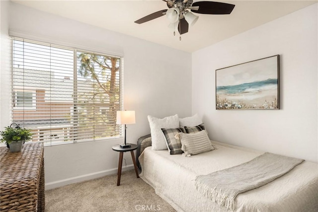 bedroom with light carpet, multiple windows, a ceiling fan, and baseboards