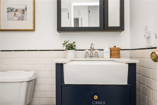 half bathroom featuring tile walls, a wainscoted wall, vanity, and toilet