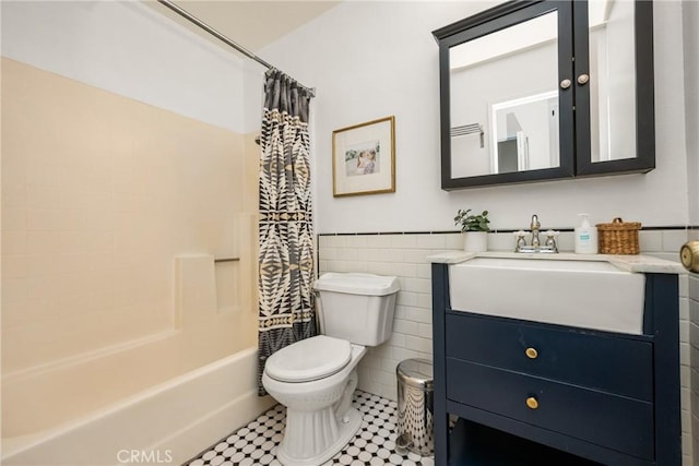 full bathroom with toilet, a wainscoted wall, vanity, tile walls, and shower / bath combo with shower curtain